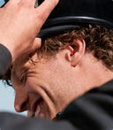 Ein Mann, der einen Motorradhelm aufsetzt, während er Alpine-Ohrstöpsel trägt.