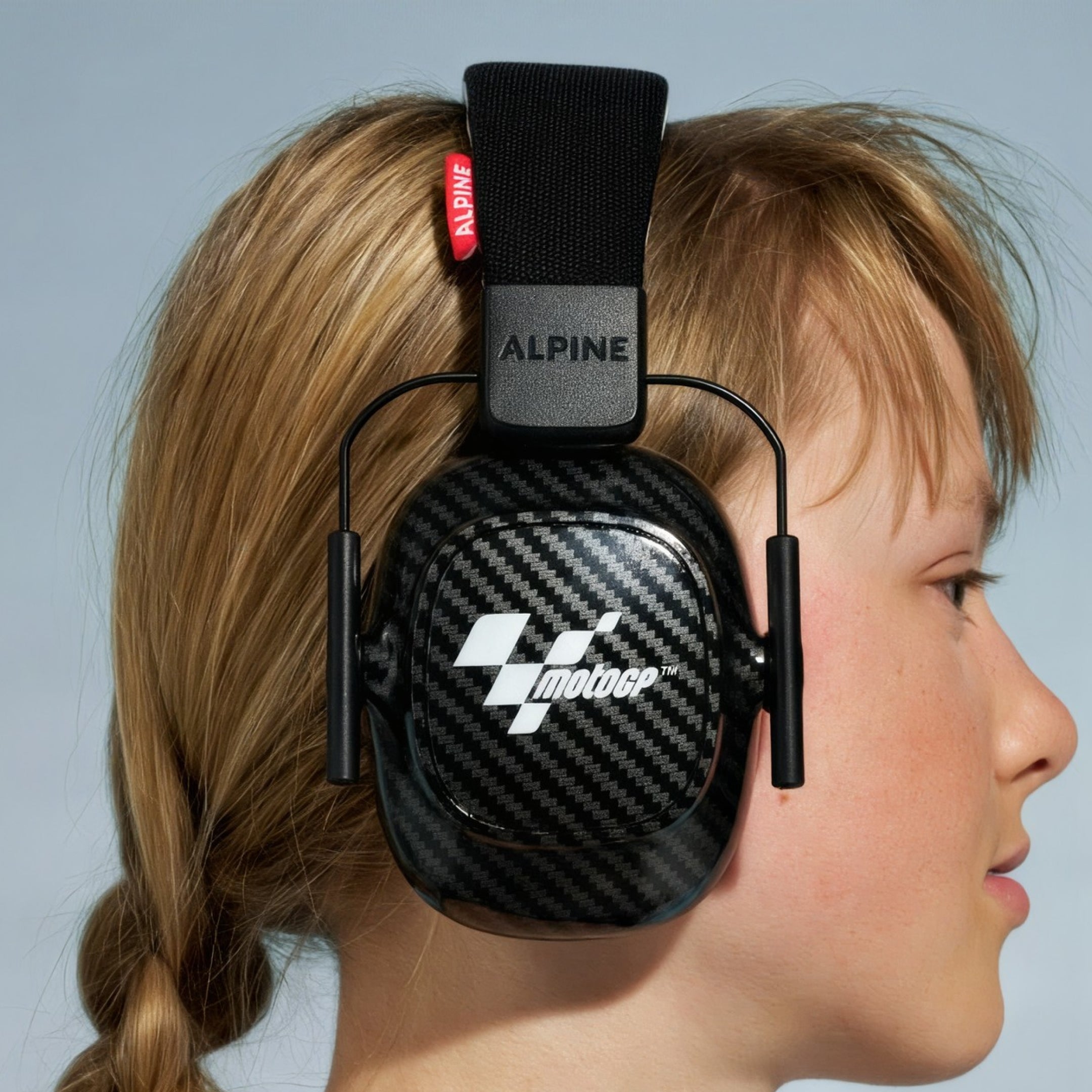 Child with a braid wearing Alpine MotoGP Racing Muffy earmuffs, side view
