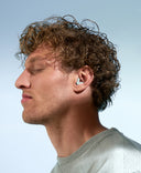 mann hat die augen geschlossen und traegt zum fokussieren silence fokus earplugs in gruen