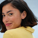 Frau traegt alpine silence earplugs in in pink ihrem ohr