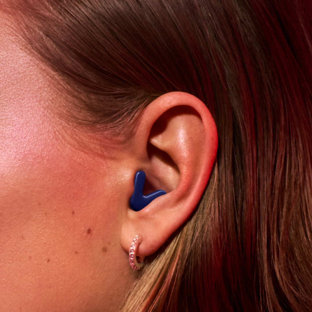 Detailed image of an ear with an Alpine Tune earplug in dark-blue showing the snug fit in ear