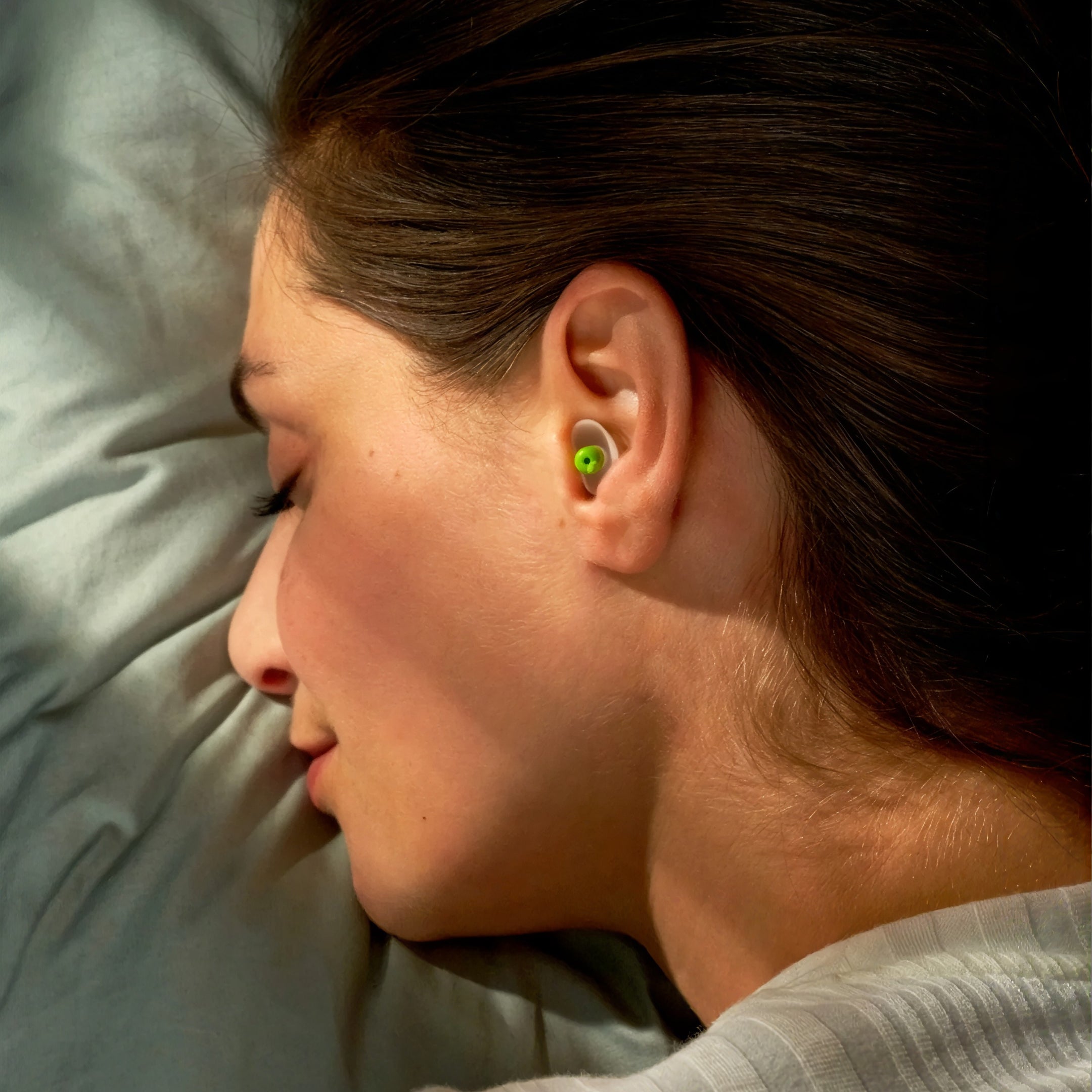 Woman sleeping on her side wearing an Alpine SleepSoft earplug