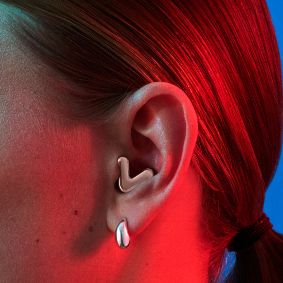 Detailed image of an ear with an Alpine Tune earplug in rose gold showing the snug fit in ear 